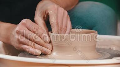 陶艺大师用手在陶工的轮子上举起泥碗的墙壁